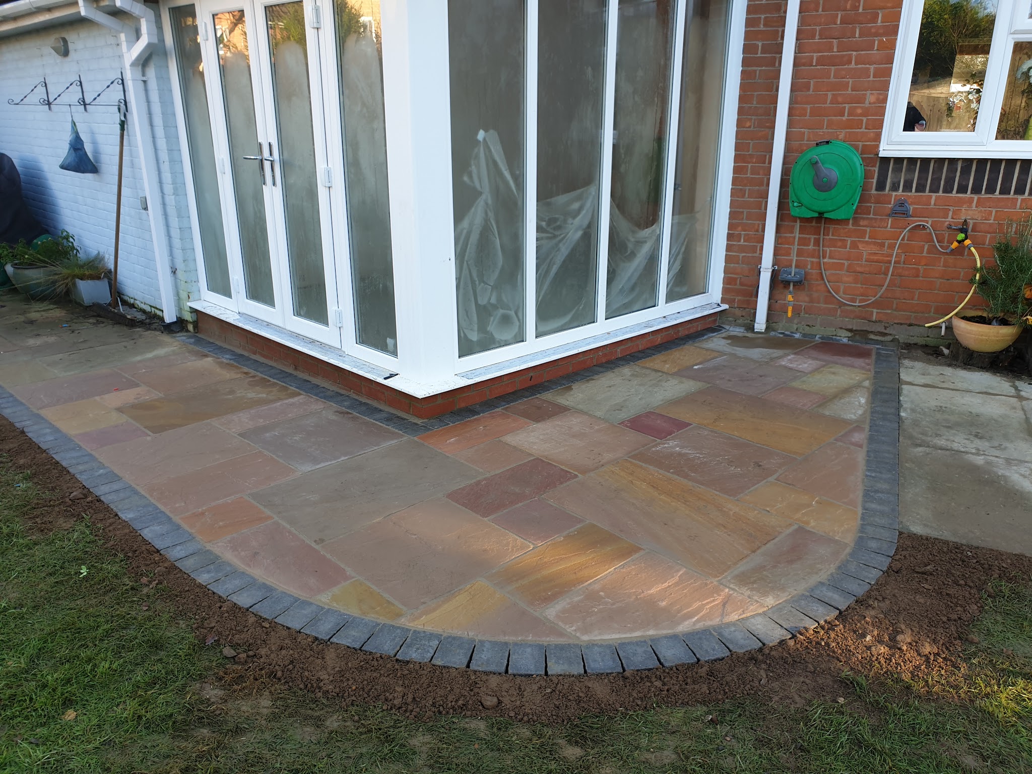 Sandstone patio with a curved block edge outside a conservatory