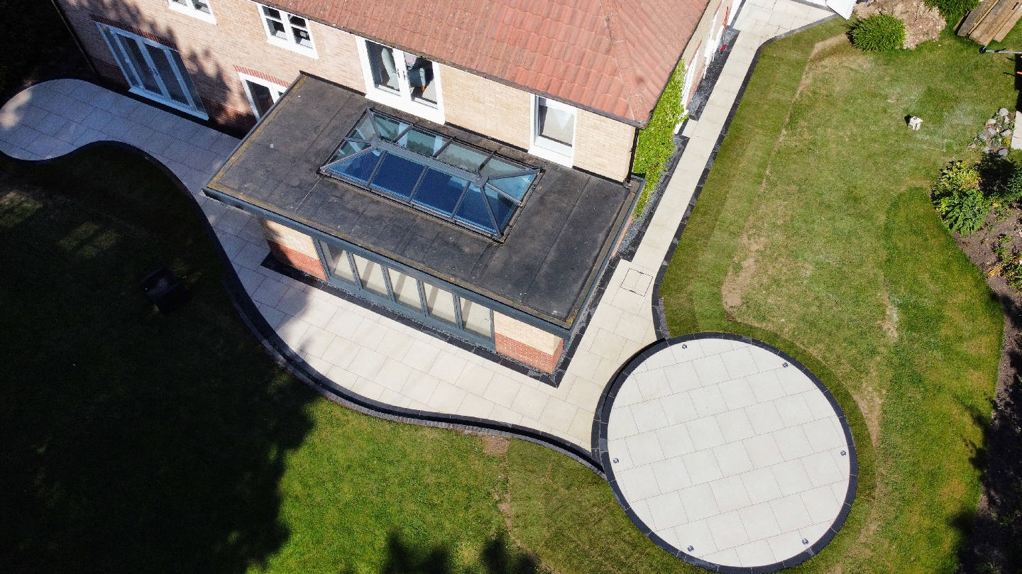 Drone view of a curved porcelain patio and circular terrace wrapping around a garden room