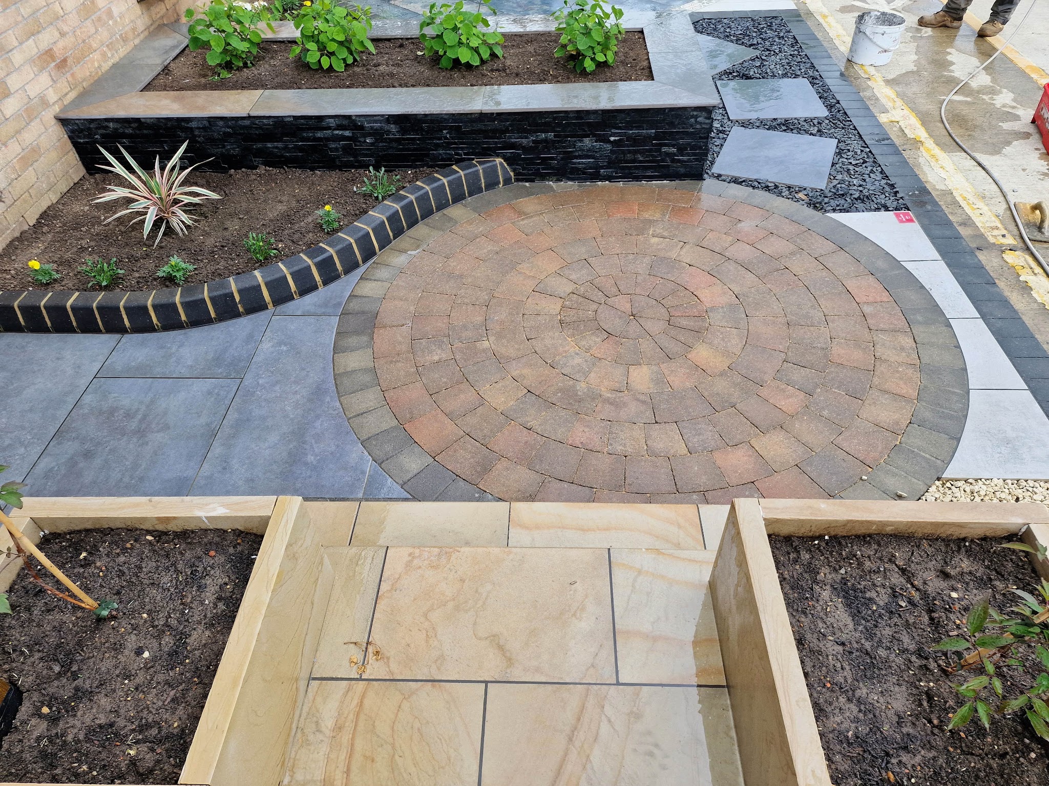 Circle feature block paving with a sandstone path and raised sleeper beds