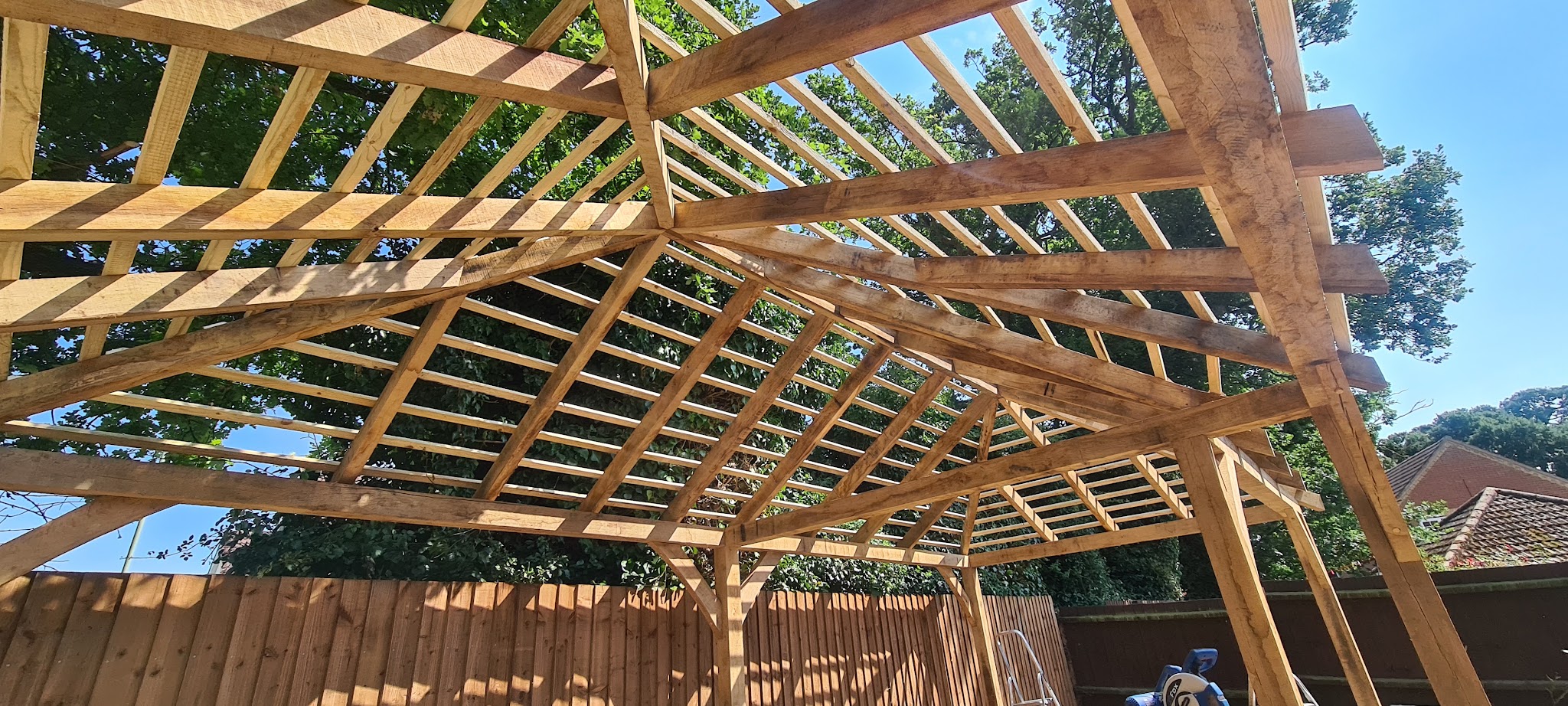 Oak pergola roof structure seen from below against a blue sky