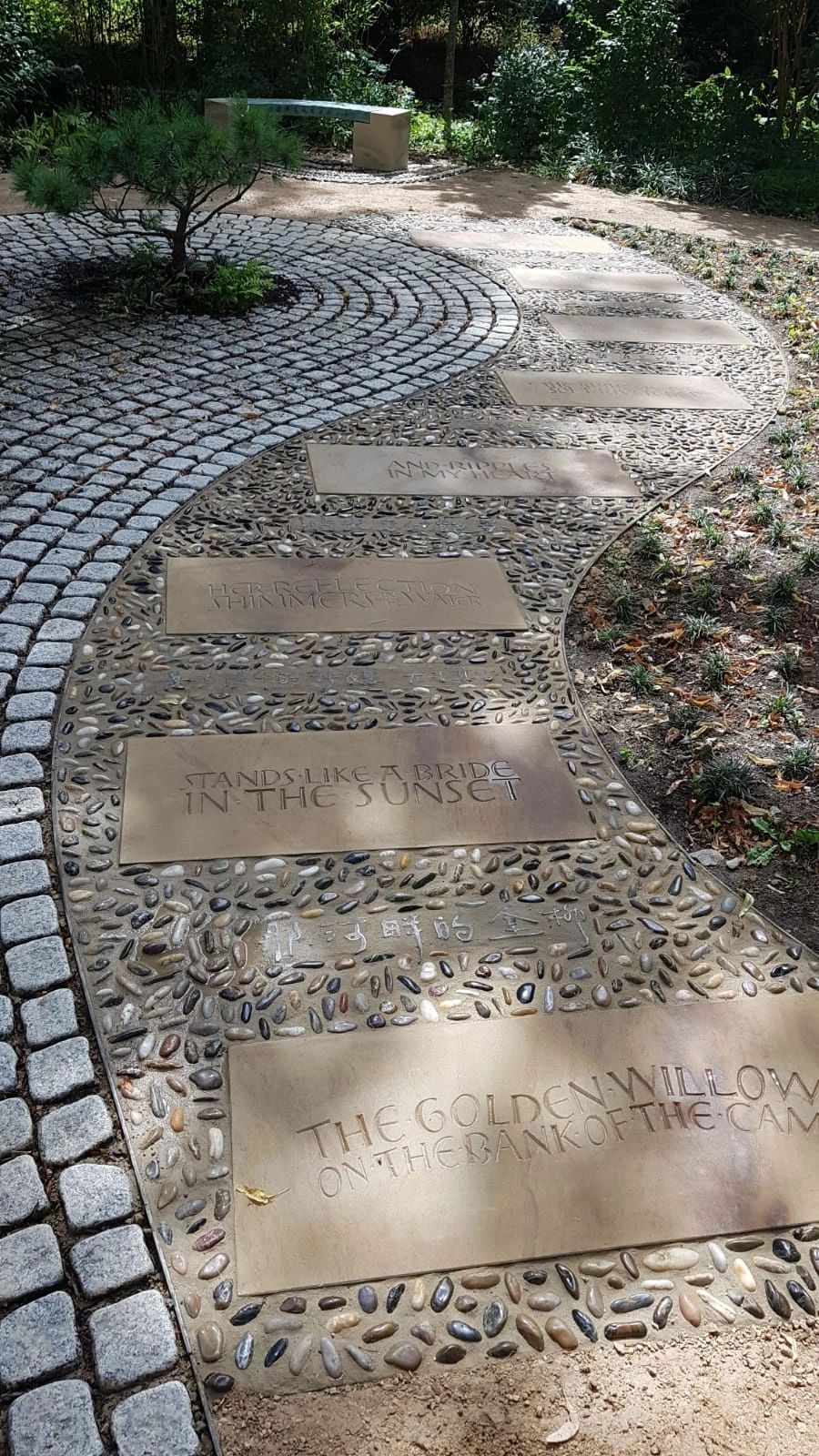 Curving pebble and granite sett path with engraved stepping stones