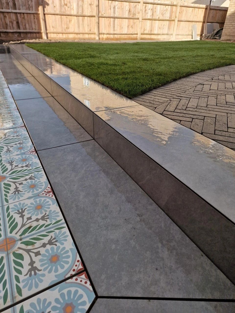 Close up of a porcelain step edge with a patterned tile riser and new lawn